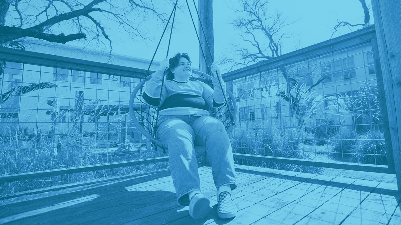 Student sits on swing in Hunt Hall Courtyard and journals.