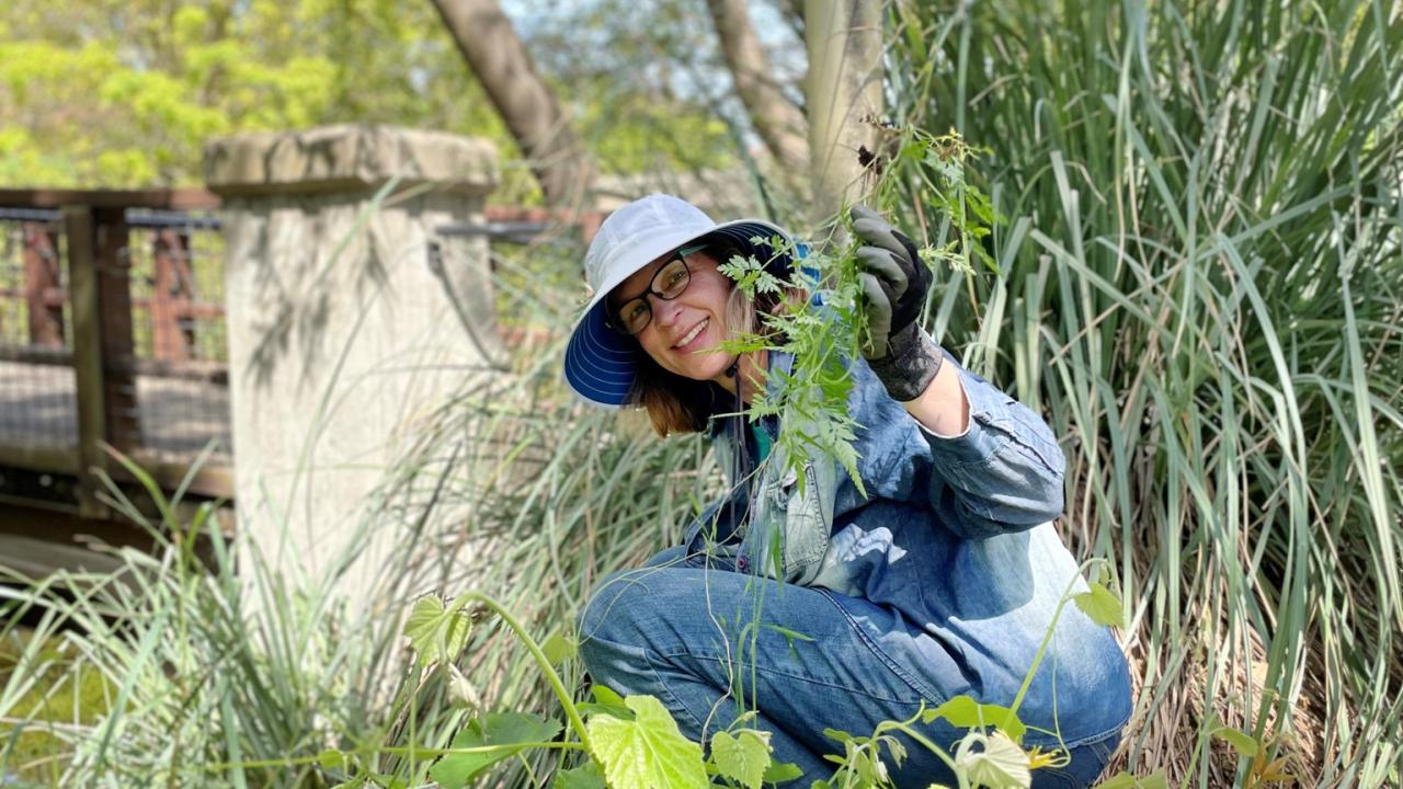 Woman weeding and smiling at the camera