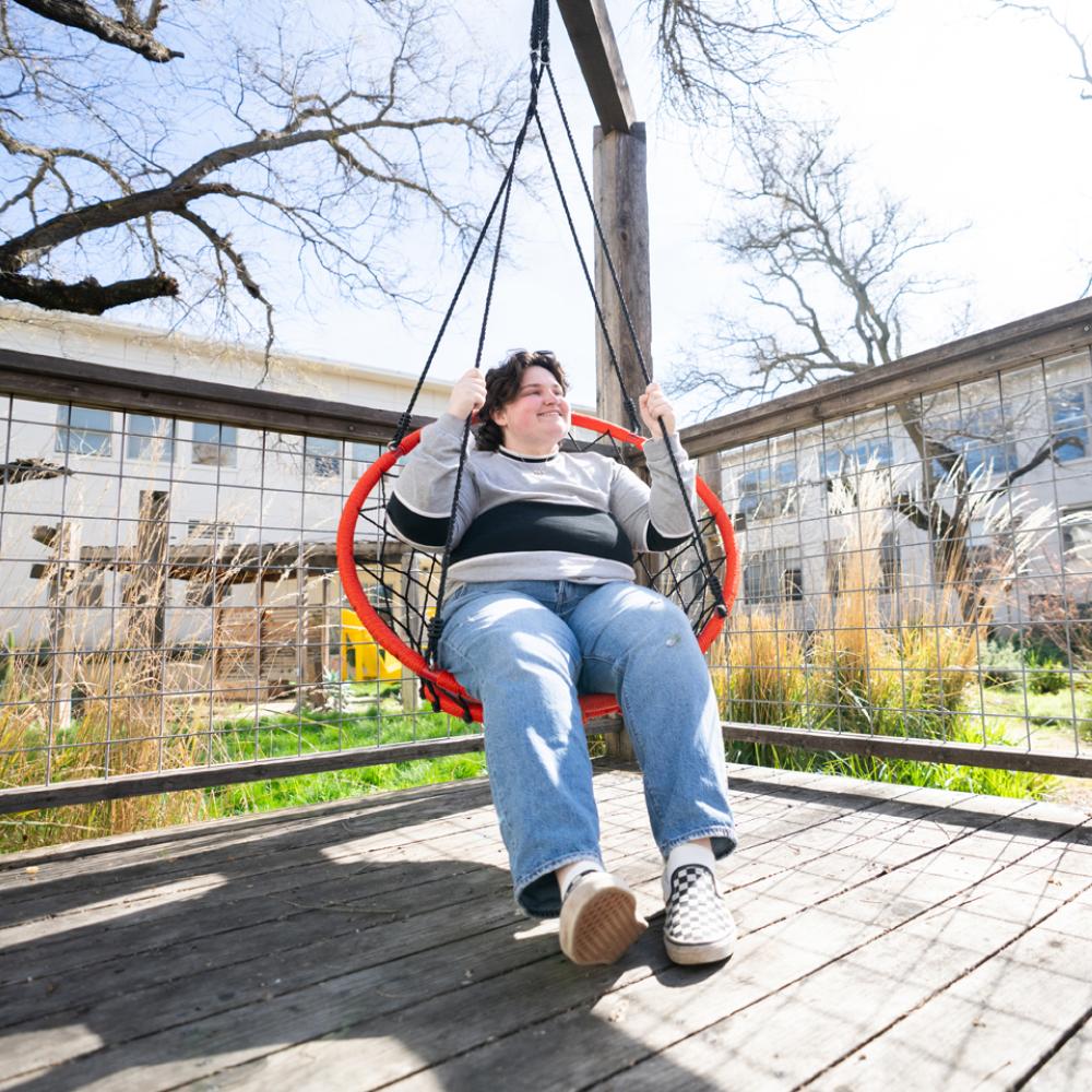 Student swinging outside in the Hunt Hall Courtyard.