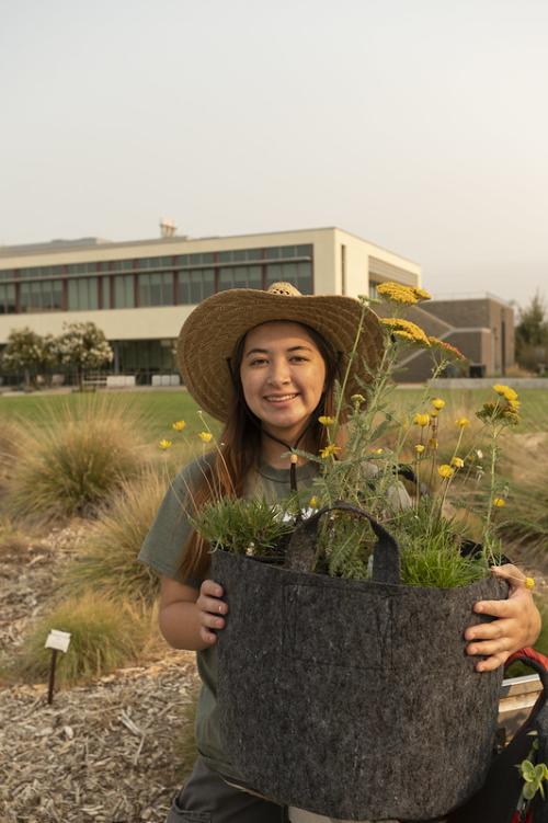 Image of Elizabeth Hursh with a potted plant for pollinators.