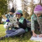 Three girl scouts fill out a Healthy Outside activity sheet