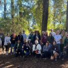 Group of volunteers smiling among trees in the Redwood Grove in the UC Davis Arboretum