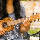 Person sits outdoors playing ukelele 